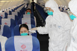 질병관리본부 국립포항검역소 대구공항지소가 최근 에볼라 바이러스 감염 의심자 대응 모의훈련을 하고 있다. 검역관들이 기내에서 감염 의심자의 귓속 체온을 재고 있다. 질병관리본부 제공