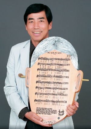 가수 호야가 어머니에 대한 그리움을 간직하기 위해 나무판으로 만든 어머니 얼굴 형상을 들고 있다.