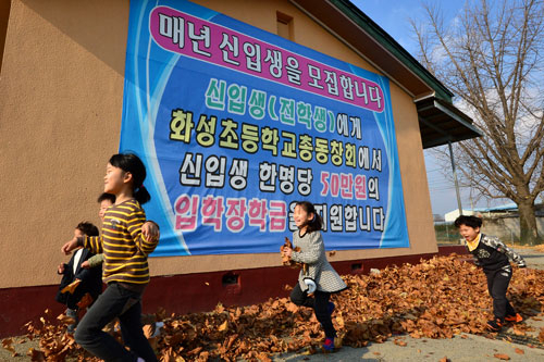 19일 오후 경산 하양초등학교 화성분교 학생들이 입학생 한 명당 50만원을 지급한다는 내용의 신입생 모집 플래카드 앞을 뛰어다니며 즐거운 시간을 보내고 있다. 정운철 기자 woon@msnet.co.kr