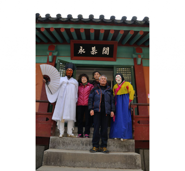 하회별신굿탈놀이 부네탈과 이매탈이 검무산 정상에 올라 준공을 앞두고 있는 산아래 경상북도 신청사를 가리키고 있다. 멀리 하회마을을 휘감아 흐르는 낙동강이 보인다.