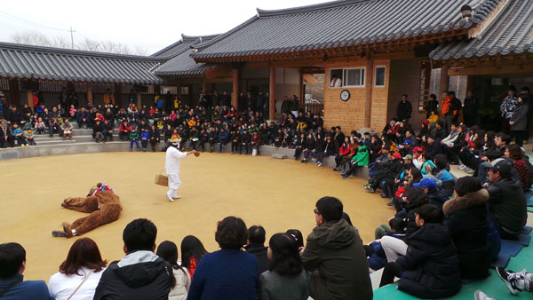 하회별신굿탈놀이가 공연되고 있는 하회마을 탈놀이전수관. 기온이 영하로 떨어지는 겨울철임에도 객석이 거의 다 찰 정도로 관객들이 몰리고 있다. 사진은 백정탈이 갓 잡은 소에서 떼어 낸 뜨끈뜨끈한 염통을 사라고 하면서 관객들을 희롱하고 있다.