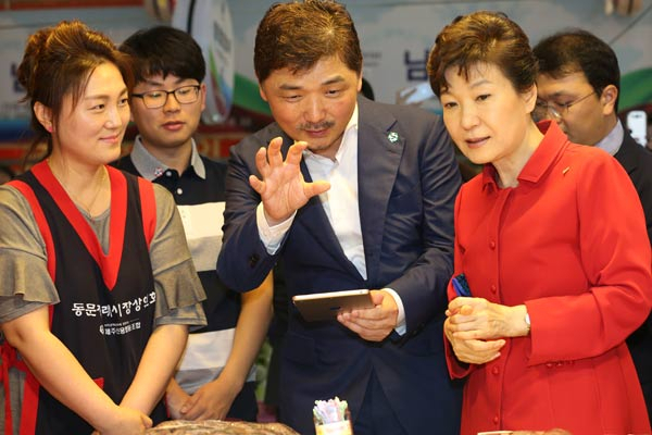 박근혜 대통령이 26일 제주 동문시장을 방문, 김범수(가운데) 다음카카오 이사회 의장으로부터 ICT기술활용을 통한 전통시장 지원에 대해 설명을 듣고 있다. 연합뉴스