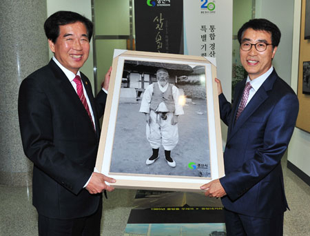 최영조(왼쪽) 경산시장이 사진전에 전시된 고 박순백 씨의 사진을 대형 액자에 넣어 손자 태일 씨에게 전달했다.