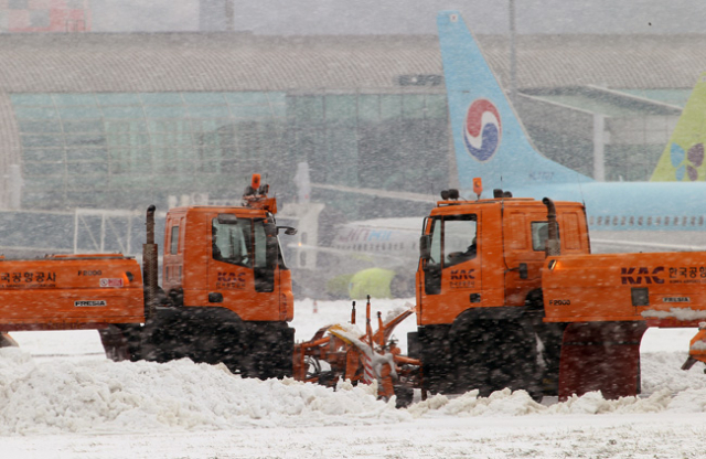 사상 초유의 제주공항 항공기 중단 사태가 3일째 이어진 25일 운항재개 결정이 내려진 가운데 활주로에서 제설작업이 이뤄지고 있다.연합뉴스