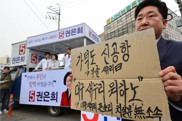 6일 오후 대구 칠성시장에서 열린 무소속 유승민 동을, 류성걸 동갑, 권은희 북갑 후보 합동 유세에서 한 지지자가 새누리당 부산지역 후보들이 개최한 가덕도 신공항 유치 공약이행 서약식에 대해 침묵으로 일관하고 있는 새누리당 대구시당을 꼬집는 피켓을 들고 무소속 후보들을 응원하고 있다. 정운철 기자 woon@msnet.co.kr