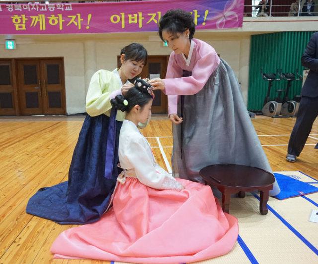 12일 대구 중구 경북여고에서 열린 계례(禮)에서 진행을 도와주는 시자(侍者)와 학부모가 성년식을 치르는 학생에게 비녀를 꽂아주고 있다. 허현정 기자