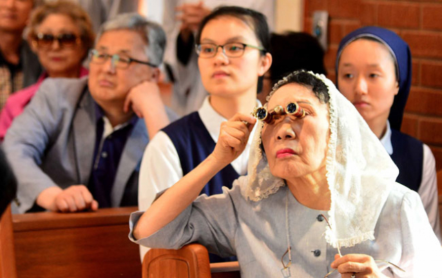 한 신자가 망원경으로 미사를 지켜보고 있다. 김영진 기자 kyjmaeil@msnet.co.kr