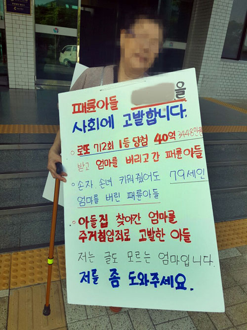 한 할머니가 지난 5일 오후 경남 양산시청 앞 현관에서 로또에 당첨된 뒤 돌변한 패륜 아들을 고발한다며 피켓을 든 채 1인 시위를 벌이고 있다. 연합뉴스
