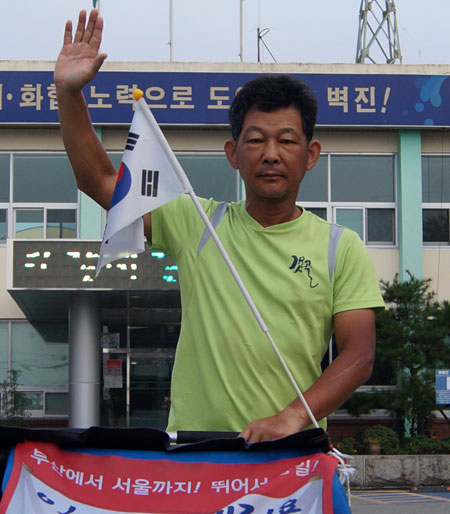 광복절을 앞두고 부산에서 서울까지 통일 마라톤에 도전 중인 강명구 씨가 9일 오전 7시 성주군 벽진면사무소를 출발하기 전 손을 들어 완주를 약속했다. 전병용 기자
