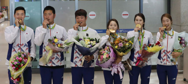리우 올림픽 전 종목 석권의 위업을 달성한 한국 양궁 대표팀 구본찬, 김우진, 이승윤, 장혜진, 기보배, 최미선(왼쪽부터)이 16일 인천공항을 통해 귀국, 메달을 들어 깨무는 포즈를 취하고 있다. 연합뉴스