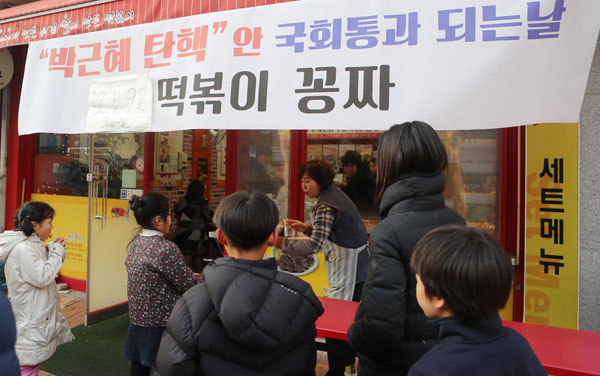 9일 오후 전북 전주시 완산구 한 음식점 업주가 탄핵안이 국회를 통과하자 주민에게 떡볶이를 무료로 제공하고 있다. 연합뉴스