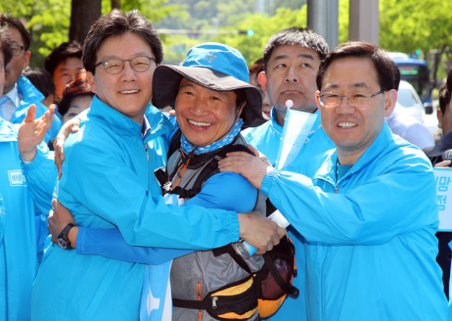 몸은 함께, 마음은 따로? 유승민(왼쪽) 바른정당 후보가 27일 오전 대구 수성구 담티역에서 새로운 보수를 알리며 국토대장정 중인 이학재(가운데) 의원을 만나 포옹하고 있다. 오른쪽은 어깨를 주물러 주는 주호영 공동선대위원장.