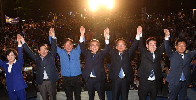 문재인 후보가 10일 오전 서울 종로구 세종로공원에서 열린 시민들과 함께하는 개표방송에서 추미애 대표, 김부겸의원을 비롯한 경선 경쟁자들과 함께 손을 들어 지지자들에게 인사하고 있다. 연합뉴스
