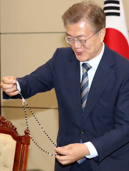 문재인 대통령이 30일 청와대에서 교황청 특사로 다녀온 김희중 대주교(한국 천주교 주교회의 의장)로부터 프란치스코 교황이 선물한 묵주를 전달받은 뒤 자세히 보고 있다. 연합뉴스