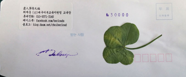 최재운 전 교육장이 나눠주는 네잎클로버 봉투.