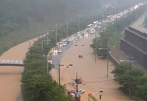 부산지역에 호우경보가 내려진 11일 오전 부산 강서구 지하과학산단로 일대 도로가 인근 하천이 범람해 차량이 통제되고 있다. 엘리시아 아파트 입주민 까페 캡처=연합뉴스
