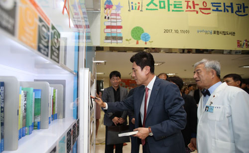 포항시는 41개의 작은도서관과 5개의 스마트 작은도서관을 운영하면서 새로운 문화를 만들어가는 첨병 역할을 톡톡히 하고 있다. 포항의료원 로비에서 열린 스마트 작은도서관 개관식에서 이강덕(가운데) 포항시장이 무인대출시스템을 살펴보고 있다. 포항시 제공
