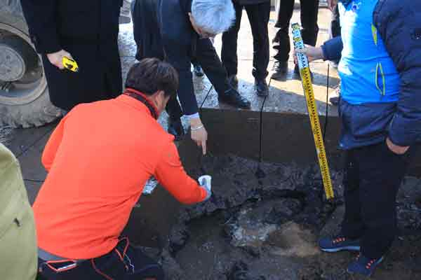 지난 6일 부산국토관리청이 주도한 동공 굴착공사 중 굴착기가 아스콘을 걷어낸 자리에서 물이 발견되자 공무원 등이 동공 깊이, 수돗물 여부 등을 확인하고 있다.