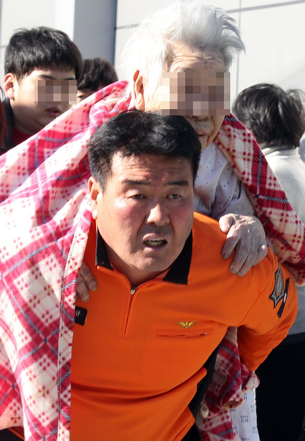 26일 오전 7시 30분쯤 경남 밀양시 가곡동 세종병원에서 불이 나 소방대원이 환자를 이송하고 있다. 연합뉴스