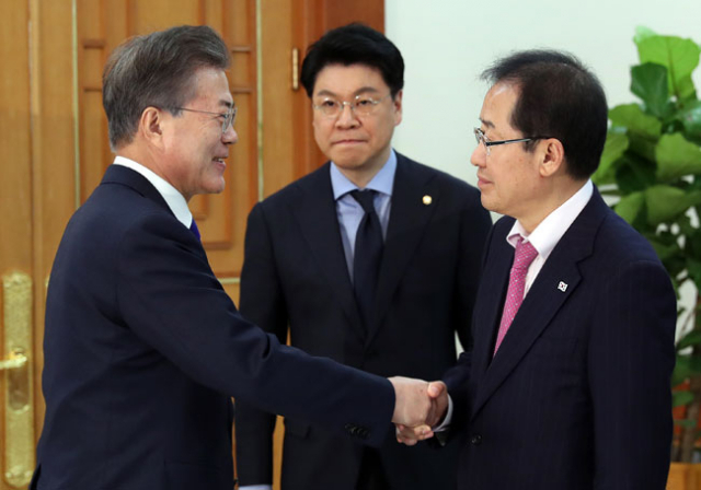 문재인 대통령이 7일 낮 청와대에서 여야 대표 오찬 간담회에 참석한 자유한국당 홍준표 대표와 악수하고 있다. 가운데는 장제원 한국당 수석 대변인. 연합뉴스