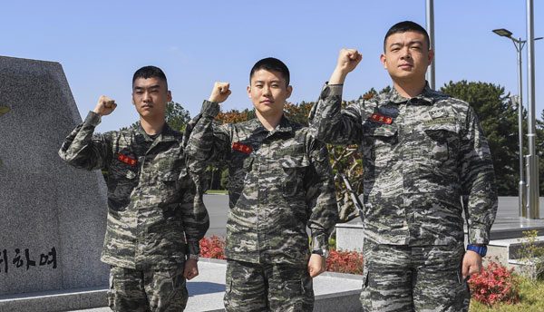 취객에게 폭행을 당하던 편의점 여성 종업원을 구한 이규현 하사, 하성준 중위, 김진규 중사(왼쪽부터)가 부대 표지석에서 파이팅을 하고 있다. 해병대 제1사단 제공