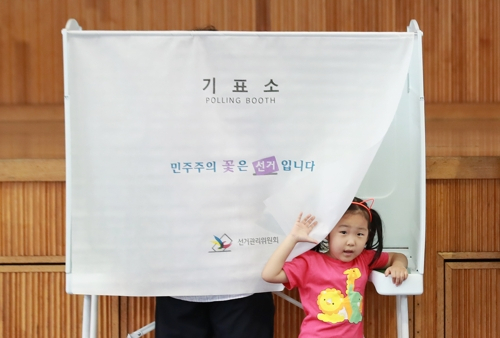 (서울=연합뉴스) 홍해인 기자 = 6.13 전국동시 지방선거가 실시된 13일 오전 서울 용산구 이태원초등학교 교육문화관에 마련된 투표소에서 아빠가 투표하는 사이 아이가 기표소의 가림막 밖으로 얼굴을 내밀고 있다. 2018.6.13 연합뉴스