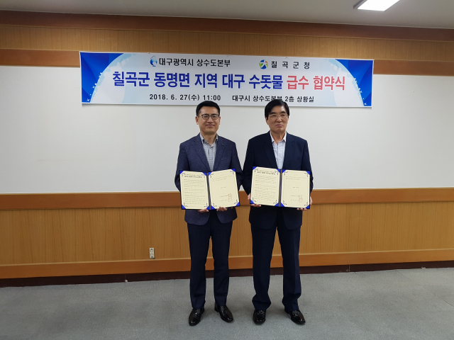 이성호(왼쪽) 대구시 상수도사업본부 시설관리소장과 금창오 칠곡군 수도사업소장이 동명면 지역 수돗물 공급을 위한 급수협약 체결서를 들어보이고 있다. 칠곡군 제공