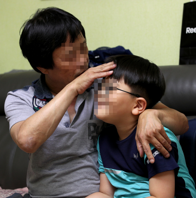 소아마비로 인한 지체장애 2급인 오명주(가명·58) 씨가 학교에서 돌아 온 막내 오상혁(가명·8)군의 머리를 쓰다듬고 있다. 상혁 군은 지적장애 1급 진단을 받았지만 최근 언어치료 등으로 학습능력이 개선되는 효과를 보고 있다. 김영진 기자 kyjmaeil@msnet.co.kr