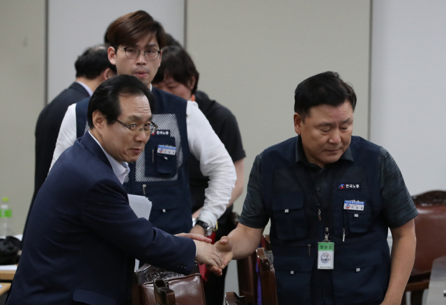 지난 14일 새벽 정부세종청사 고용노동부에서 열린 최저임금위원회 전원회의에서 내년도 최저임금이 8천350원으로 결정된 후 류장수 위원장(왼쪽)과 근로자 측 위원인 이성경 위원이 어색한 악수를 하고 있다. 내년도 최저임금이 올해보다 10.9% 오른 시간당 8천350원으로 결정됐지만, 사용자나 근로자 어느 한쪽도 만족하지 못해 앞으로 파장이 거셀 것으로 전망된다. 연합뉴스