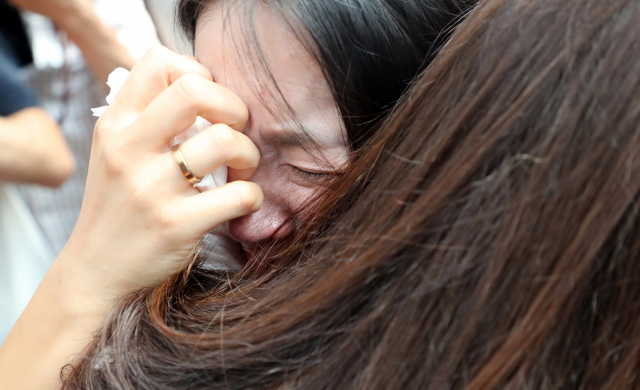 철도노사가 KTX 해고 승무원 복직을 합의한 21일 13년째 투쟁을 이어온 KTX 해고 승무원들이 서울역 플랫폼 중앙계단에서 투쟁 해단식 기자회견을 하며 부둥켜안고 눈물을 흘리고 있다. 연합뉴스