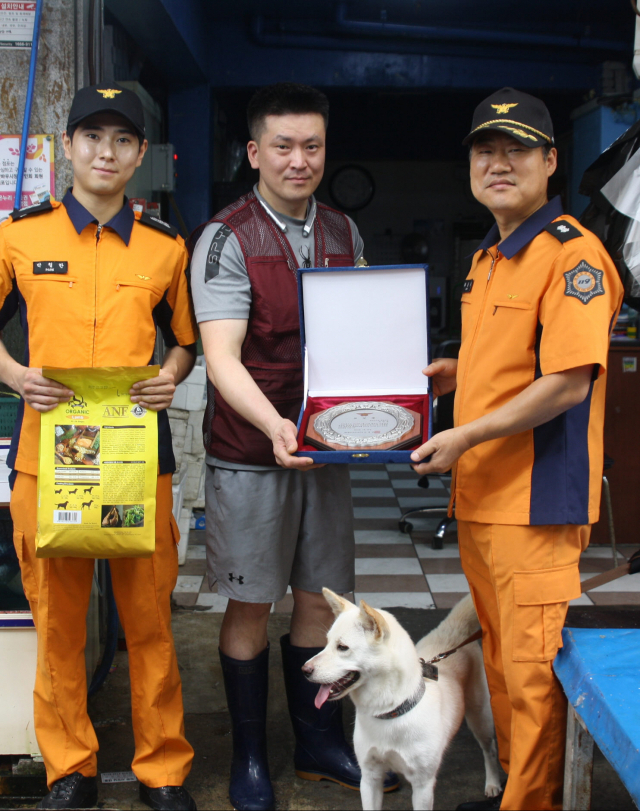 26일 오전 광주 북구 말바우시장에서 지난 22일 시장 내에서 화재가 발생하자 짖어 알린 견공에게 광주 북부소방서 대원들이 표창장을 수여하고 있다. 연합뉴스