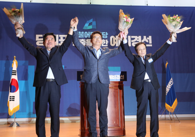 26일 오후 국회 의원회관에서 열린 더불어민주당 당대표 선출을 위한 예비경선대회에서 투표를 통해 예비경선을 통과한 3명의 후보가 손을 맞잡고 있다. 오른쪽이 이해찬 후보. 연합뉴스