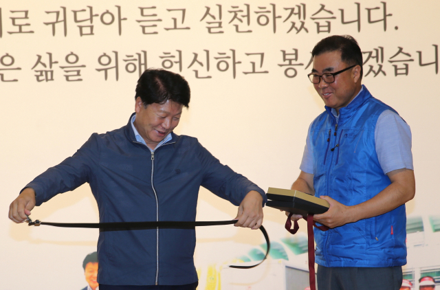 배재억(오른쪽) 성주군청공무원직장협의회장이 이병환 군수에게 군민을 위해 더 졸라매고, 더 뛰라는 의미로 허리띠와 운동화를 전달하고 있다. 성주군 제공