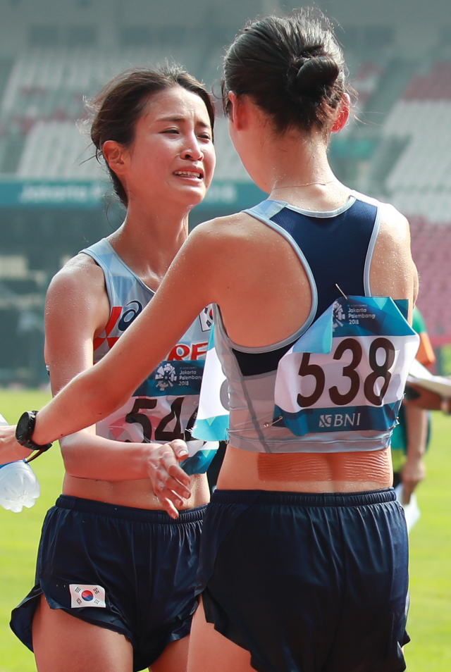 한국 김도연(왼쪽)과 최경선이 26일 오전(현지시간) 인도네시아 자카르타 겔로라 붕 카르노(GBK) 경기장 일원에서 열린 2018 자카르타-팔렘방 아시안게임(AG) 여자 마라톤 경기 결승선을 통과한 뒤 4위를 차지한 최경선(오른쪽)이 6위로 들어온 김도연과 서로를 격려하며 포옹하고 있다. 연합뉴스