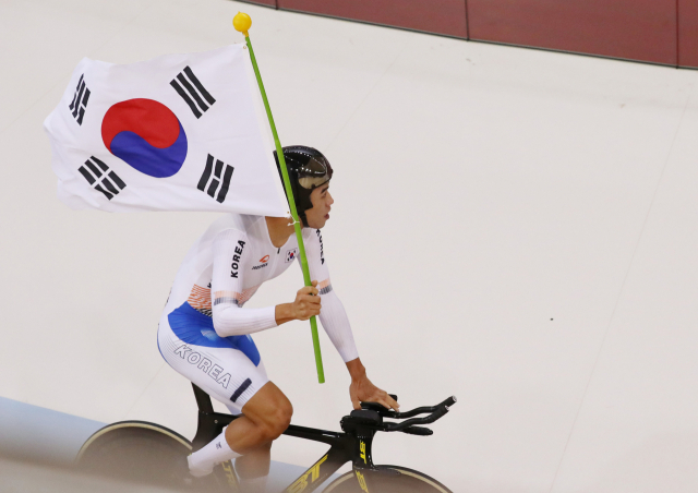 29일 오후 (현지시간) 인도네시아 자카르타 인터내셔널 벨로드롬에서 열린 2018 자카르타-팔렘방 아시안게임 사이클 트랙 남자 개인추발 결승. 한국 박상훈이 일본을 꺾고 금메달을 획득, 태극기를 들고 트랙을 돌고 있다. 연합뉴스