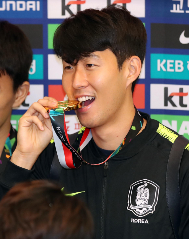 2018 자카르타-팔렘방 아시안게임에서 금메달을 획득하며 대회 2연패를 달성한 축구대표팀 손흥민이 3일 오전 인천국제공항으로 귀국한 뒤 해단식에서 금메달을 입에 물고 있다. 연합뉴스