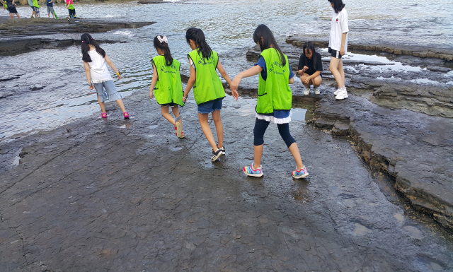 공룡발자국을 관찰하는 대구녹색사관학교 생도들이 발자국을 따라 걷고 있다.