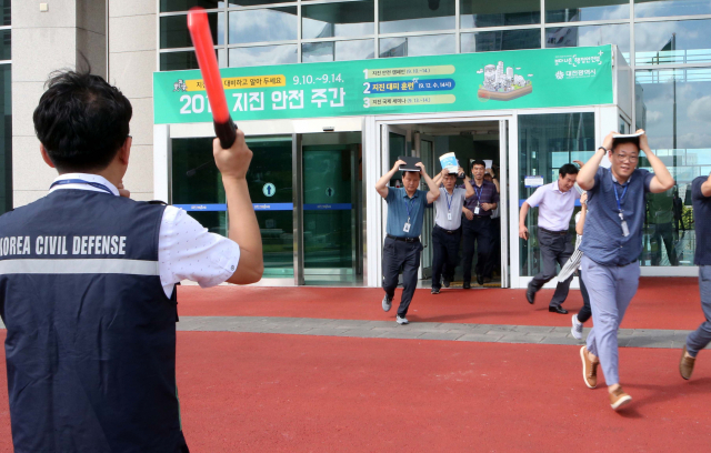 12일 오후 대전시청사에서 열린 지진 대피훈련에 참가한 공무원들이 머리를 보호하며 재빨리 청사 건물을 빠져나가고 있다. 연합뉴스