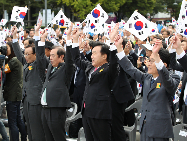 9일 서울 종로구 광화문 광장 세종대왕 동상 앞에서 열린 제572돌 한글날 경축식에 더불어민주당 이해찬 대표(왼쪽부터), 자유한국당 김병준 비상대책위원장, 바른미래당 손학규 대표, 정의당 윤소하 원내대표가 태극기를 들고 만세삼창을 하고 있다. 연합뉴스