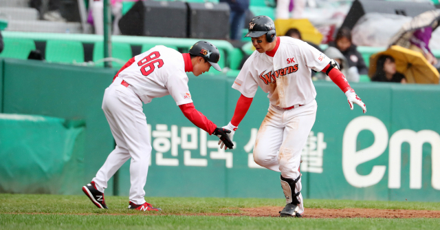 28일 오후 인천 SK행복드림구장에서 열린 2018 프로야구 플레이오프 2차전 넥센 히어로즈 대 SK 와이번스의 경기. 5회말 2사 SK 김강민이 역전 솔로홈런을 터트린 뒤 3루에서 코치와 하이파이브를 하고 있다. 연합뉴스