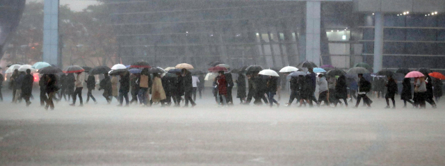 부산지역에 호우주의보가 발령된 8일 오후 부산 해운대구 벡스코 제1전시장 야외광장에서 시민들이 우산을 들고 장대빗속을 걸어가고 있다. 연합뉴스