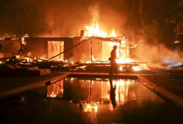A firefighter walks by the a burning home in Malibu, Calif., Friday, Nov. 9, 2018. A Southern California wildfire continues to burn homes as it runs toward the sea. Winds are blamed for pushing the fire through scenic canyon communities and ridgetop homes. (AP Photo/Ringo H.W. Chiu) 美 캘리포니아 산불