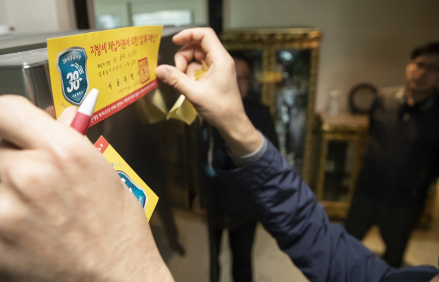 14일 오전 서울시 세금조사관이 서울시 강남구의 한 고액상습체납자 가택수색 중 압류재산 스티커를 붙이고 있다. 연합뉴스