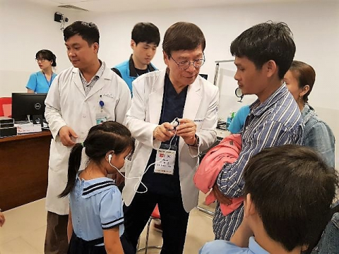 합동의료봉사단이 귀가 어두운 어린이 환자에게 보청기를 설명해 주고 있다.