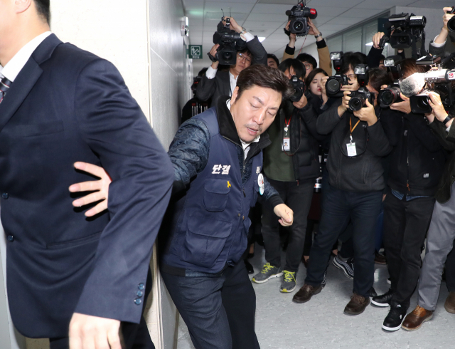 장경호 전국금융산업노동조합 우리카드 지부장(가운데)이 26일 오전 국회 의원회관에서 열린 카드수수료 개편방안 당정협의 회의장에 진입을 시도, 국회 관계자에게 저지당하고 있다. 연합뉴스