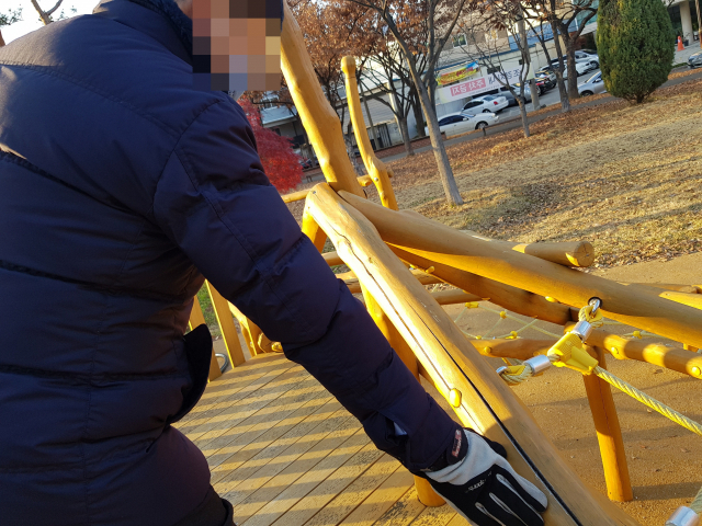 퀸스로드 광장에 설치된 어린이놀이시설의 아까시나무가 갈라져 있다. 한 주민이 목재를 가리키는 모습. 채원영 기자