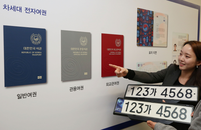21일 오후 서울 종로구 국립현대미술관에서 열린 제2차 공공디자인위원회의에 앞서 관계자가 차세대 전자여권과 숫자가 7자리로 늘어난 새 승용차 번호판을 선보이고 있다. 새 여권은 2020년 중, 번호판은 2019년 9월부터 발급할 예정이다. 연합뉴스
