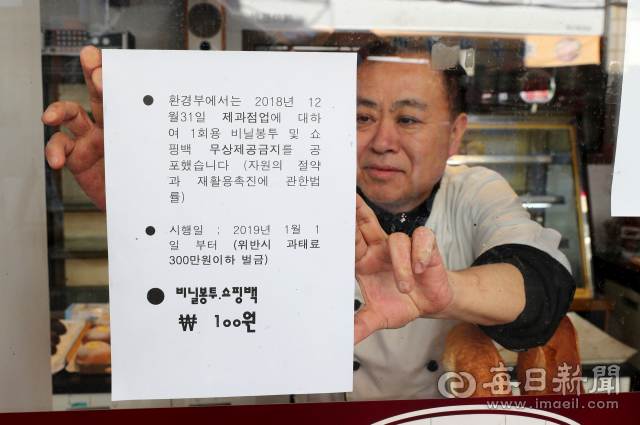 2일 대구 남구 한 제과점 주인이 일회용 비닐봉투를 무상으로 제공하지 않는다는 안내문을 붙이고 있다. 새해 1일부터 대형마트와 슈퍼마켓에서는 일회용 비닐봉투 사용이 금지되고, 제과점에서는 무상으로 제공하지 못한다. 위반시 최대 300만원의 과태료가 부과된다. 성일권 기자 sungig@imaeil.com