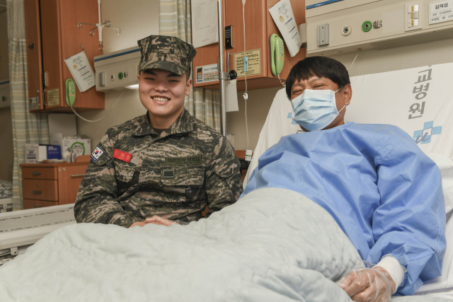 해병대 김태형 상병이 간이식 수술 후 병상에서 회복 중인 아버지의 손을 잡고 활짝 웃고 있다. 해병대 1사단 제공