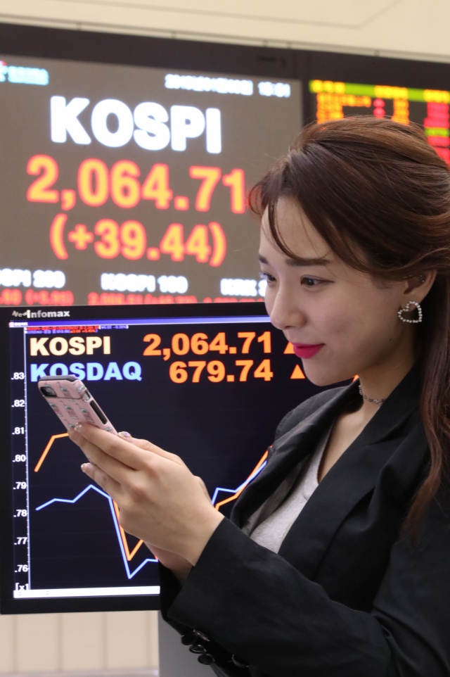 코스피가 외국인과 기관의 동반 매수에 힘입어 2,060선을 회복한 9일 서울 여의도 한국거래소의 주식시세 전광판 앞에서 한 직원이 휴대전화를 보고 있다. 코스피는 전 거래일보다 39.44포인트 오른 2,064.71에 장을 마쳤다. 코스닥지수는 11.25포인트(1.68%) 오른 679.74로 마감했다. 연합뉴스